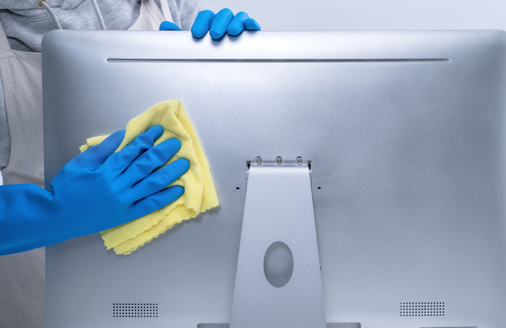 Office cleaner wiping the back of a computer monitor